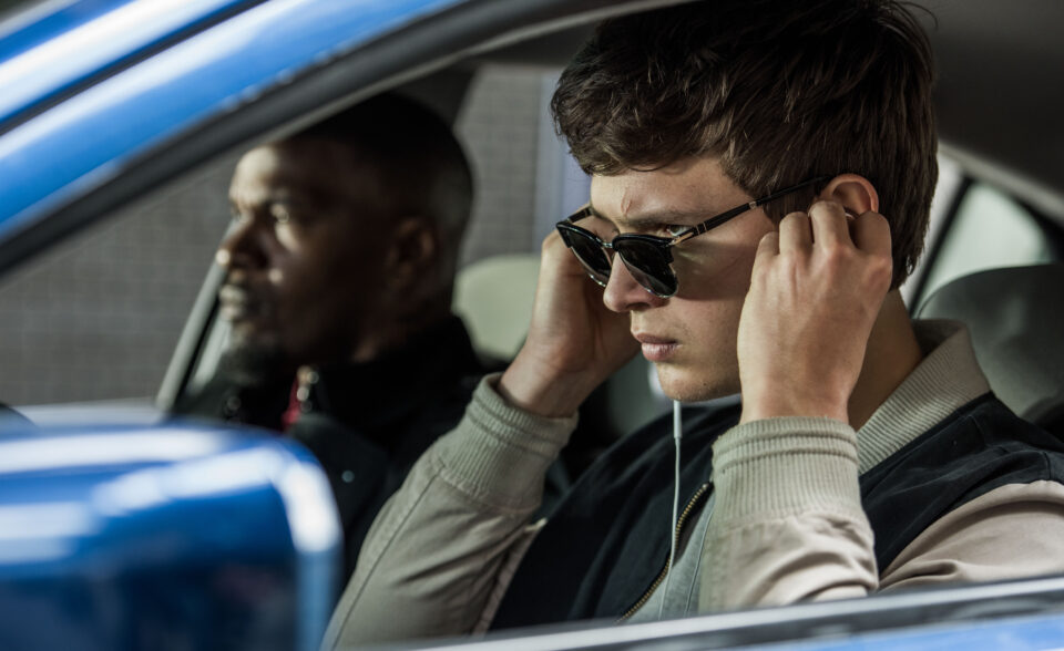 Baby (ANSEL ELGORT) and Bats (JAMIE FOXX) on the way to the post office job with Buddy (JON HAMM) and Darling (EIZA GONZALEZ) as cops pull up next to them in TriStar Pictures